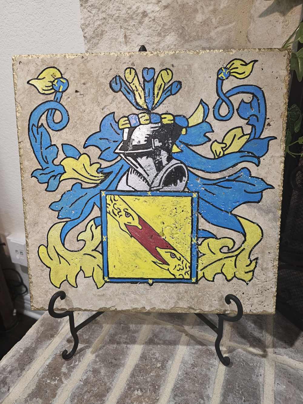 A painting of a blue and yellow coat of arms on tile.