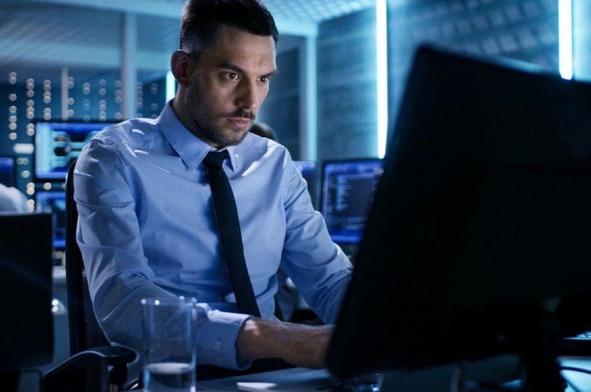 A man sitting at his computer desk looking at the screen.